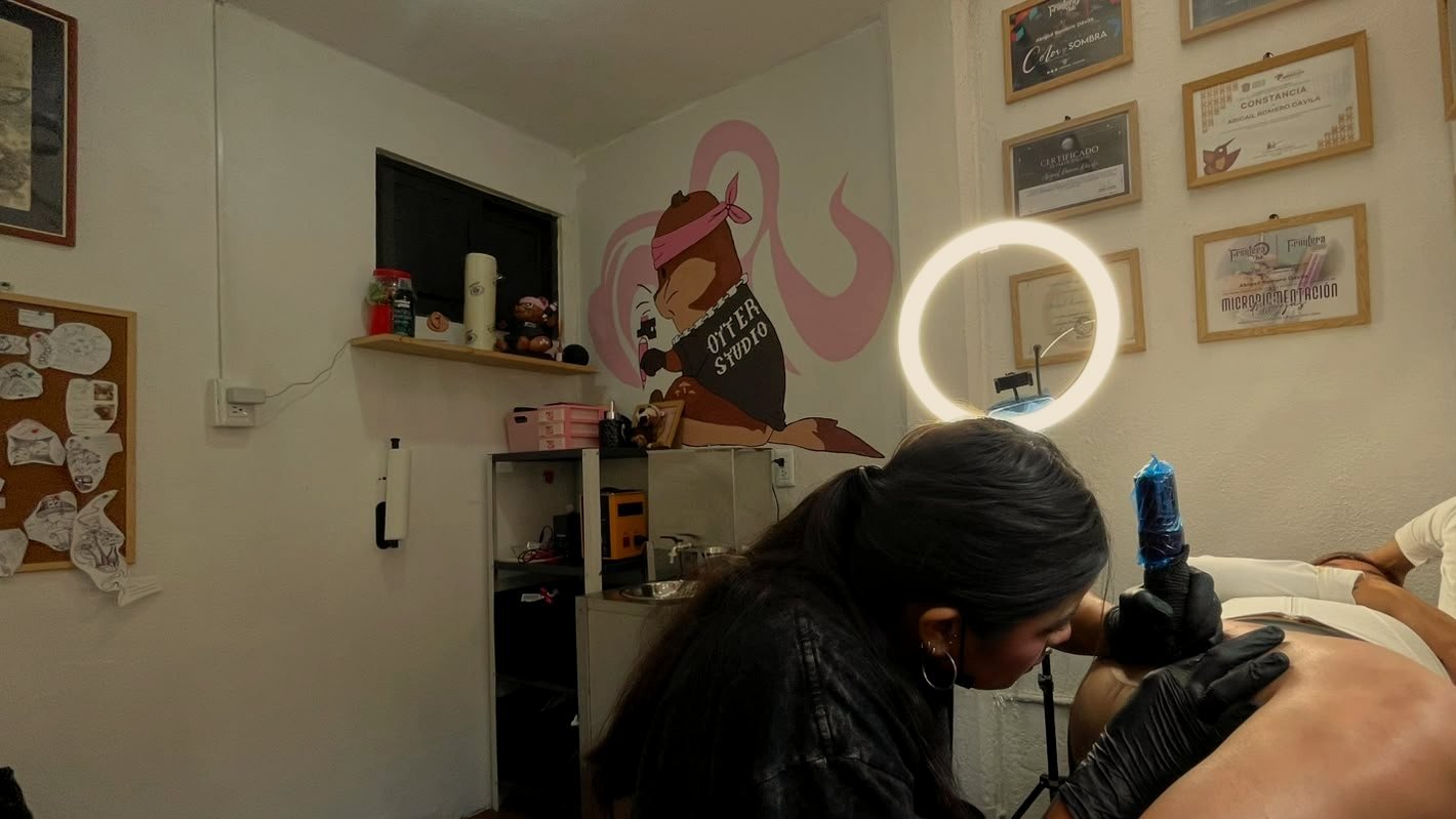 Tatuando en OtterStudio, con el mural de la nutria al fondo